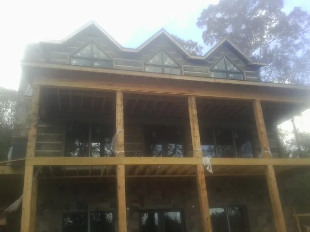 Dormers and porch framing on a large log home under construction — Roof Coating work by our crew in Eden