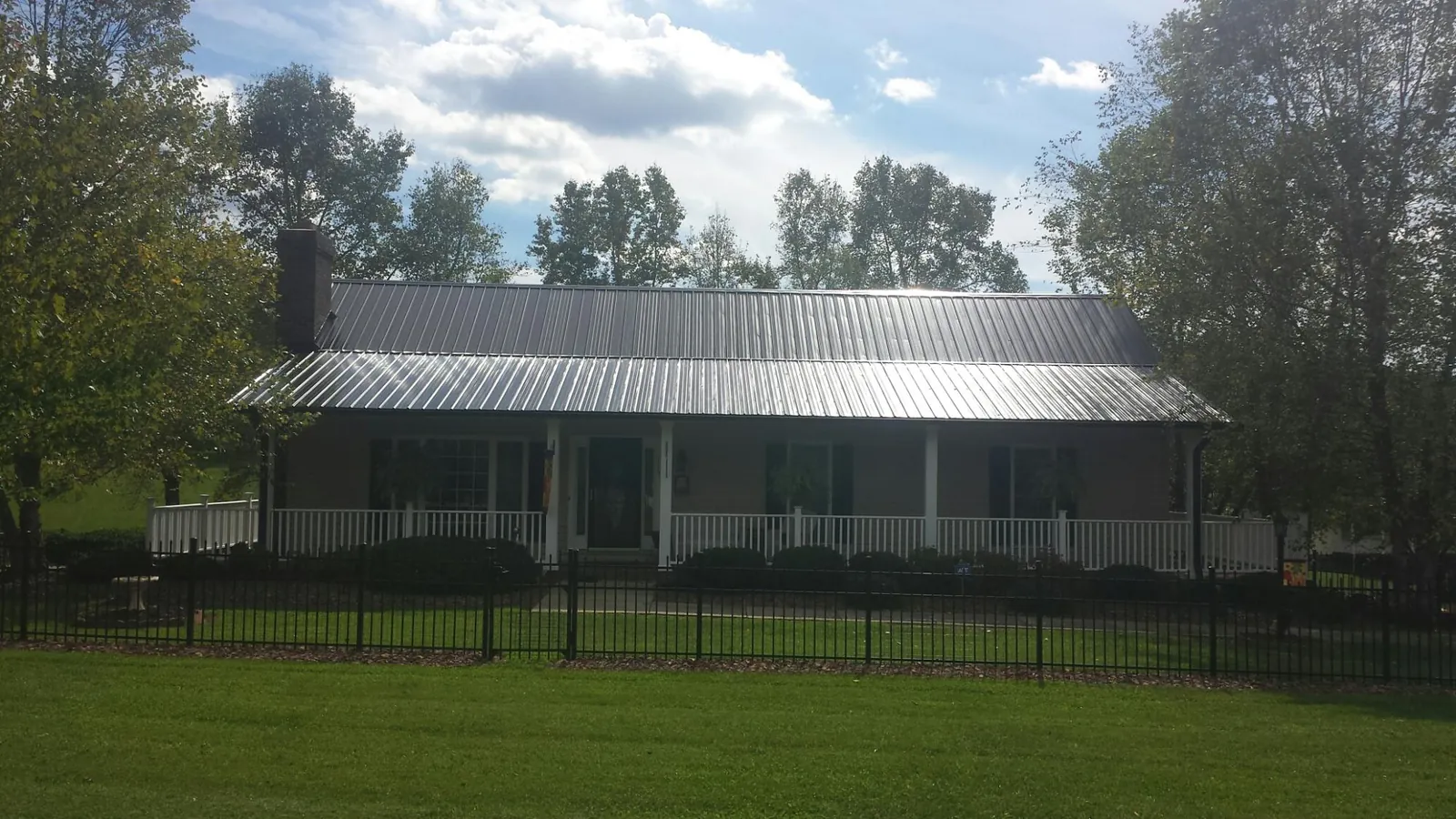 Gray metal roof on a brick ranch with a full width front porch — Gutter Guard Installation work by our crew in Eden